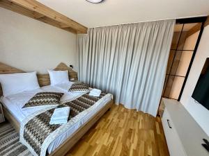a bedroom with a bed with pillows and a television at Apartman A55 Aparthotel Vučko privatni apartman in Jahorina