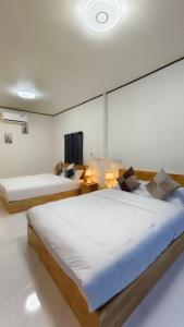 zwei Betten in einem großen Zimmer mit weißen Wänden in der Unterkunft อินทนนท์ บ้านพักเล่าจู Inthanon Laoju House in Ban Na Yang