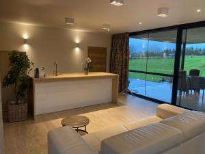 a living room with a couch and a table and a kitchen at Au Charme des Fagnes in Malmedy