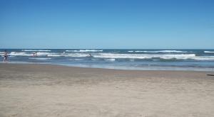 eine Gruppe von Menschen im Wasser am Strand in der Unterkunft Aconchegante apto em Capao da Canoa in Capão da Canoa