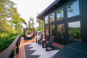 eine Holzterrasse mit Bänken an einem Haus in der Unterkunft Private Lux Getaway Hot Tub Double Shower Cabana in Campton