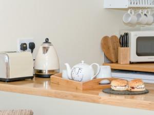 a kitchen counter with a microwave and a cutting board with sandwiches at Cherry Laurel in Thornton Dale