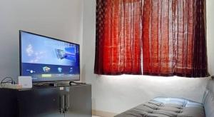 a living room with a couch and a flat screen tv at COZY 2BR Pinewood Apt Jatinagor in Cilimus 2
