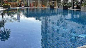 a large swimming pool with blue water in a building at COZY 2BR Pinewood Apt Jatinagor in Cilimus 2
