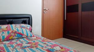 a bedroom with a bed with a comforter and a door at COZY 2BR Pinewood Apt Jatinagor in Cilimus 2