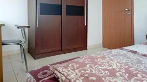 a bedroom with a bed and a chair and a closet at COZY 2BR Pinewood Apt Jatinagor in Cilimus 2 +1 photo