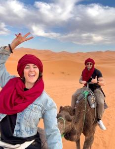 two people riding on a camel in the desert at Desert Pearl Camp in Merzouga +152 photos