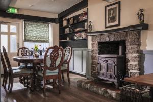 a dining room with a table and a fireplace at Cromwell Arms in Bovey Tracey
