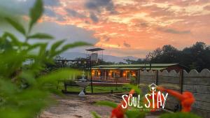 ein kleines Haus mit Sonnenuntergang im Hintergrund in der Unterkunft Soulstay Resort in Chinchavli