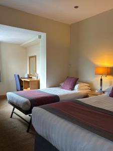 a hotel room with two beds and a desk at St. Davids Cross Hotel in St. Davids