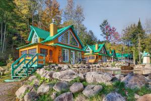 une maison dans les bois avec un étang en face dans l'établissement Domaine Rivière Sacacomie - Chalet Le Cardinal, à Saint-Alexis-des-Monts