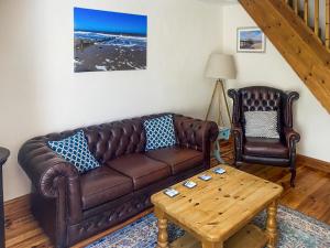 a living room with a brown leather couch and two chairs at Jenny's Cottage 27553 in Mundesley