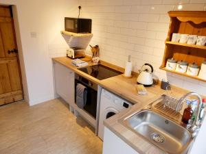 a kitchen with a sink and a stove top oven at Jenny's Cottage 27553 in Mundesley
