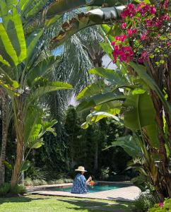 a woman in a hat sitting next to a swimming pool at Villa Vicuña Salta Hotel Boutique in Salta