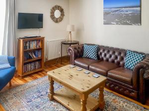 a living room with a brown leather couch and a coffee table at Jenny's Cottage 27553 in Mundesley