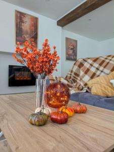 un vase avec des fleurs et des citrouilles sur une table dans l'établissement Gite de campagne avec SPA privatif, à Saint-Sauvant