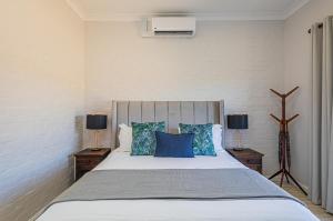 a bedroom with a large bed with blue pillows at Flensborg Studios & Penthouse - Langebaan Golf Estate in Langebaan +48 photos