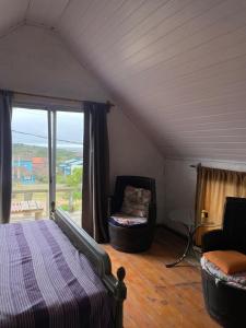 ein Schlafzimmer mit einem Bett und einem Stuhl und einem Fenster in der Unterkunft Casa Punta Del Diablo in Punta Del Diablo