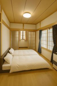 Schlafzimmer mit einem großen weißen Bett und Fenstern in der Unterkunft Deep Powder Lodge HAKUBA in Hakuba