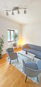 Una sala de estar con un sofá y sillas y una mesa. en Loft Klagenfurt, en Klagenfurt