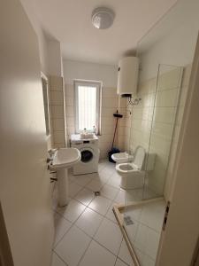 een badkamer met een wastafel, een toilet en een douche bij Home holiday kozmai in Shëngjin +34 foto's