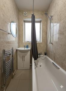 Un baño con bañera, lavabo y bañera. en East Ham House, en Londres