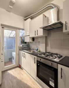 Una cocina con gabinetes blancos y un horno de estufa. en East Ham House, en Londres