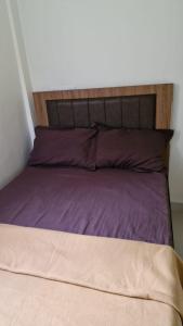 a bed with purple pillows and a wooden headboard at Hotel Kalaptaru in Nainital