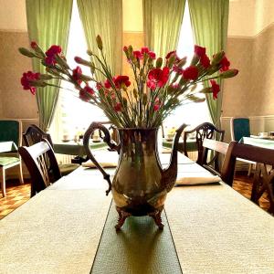 a vase filled with red flowers on a table at The Angove - Adults Only in Weymouth