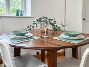 a wooden table with two bowls and glasses on it at Noddingway Cottage in Weare