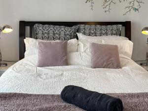 a large bed with white sheets and pillows at Noddingway Cottage in Weare +6 photos
