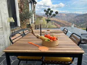 een houten tafel met een mand met fruit en groenten bij Casinha Serabigoes Arouca Passadiços Paiva in Arouca +50 foto's