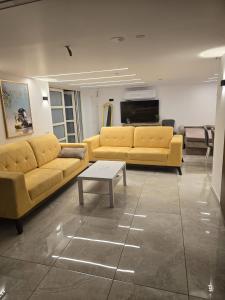 a living room with yellow couches and a coffee table at Nancy zimr 1 in Massada +2 photos