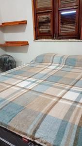 a bed with a plaid blanket on top of it at Casa por do sol Flecheiras in Flecheiras +16 photos