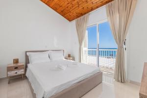 a bedroom with a bed and a large window at Wavestone Beachfront House in Meneou