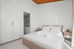 a bedroom with a white bed with two white towels on it at Wavestone Beachfront House in Meneou +14 photos