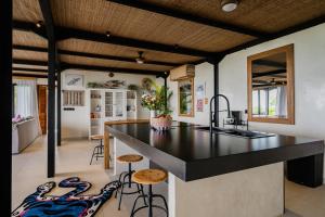 eine offene Küche mit schwarzer Arbeitsplatte und Barhockern in der Unterkunft Mar de Uluwatu - Ocean View Villa in Uluwatu