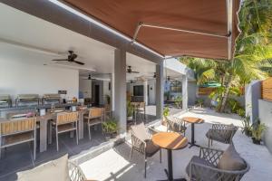 an outdoor patio with tables and chairs and a kitchen at Kirulhiya Omadhoo - Live the Island Dream in Omadhoo