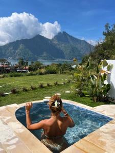 a man in a swimming pool with mountains in the background at Skyland Kintamani in Kubupenlokan