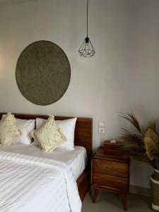 a bed with white sheets and pillows and a night stand at Skyland Kintamani in Kubupenlokan