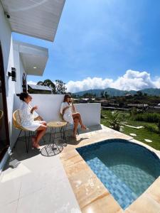 two women sitting on a balcony next to a swimming pool at Skyland Kintamani in Kubupenlokan