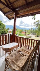 a porch with two chairs and a table on a deck at Green Corner Villa in Bukit Lawang +34 photos