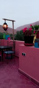 a pink balcony with a table and flowers on it at Riad La Belle Vue in Boumalne