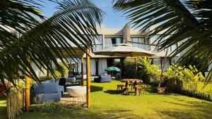 eine Terrasse mit Sonnenschirm und Tisch und Stühlen in der Unterkunft MHV Milagres - Casa OKA 37 in Passo de Camarajibe