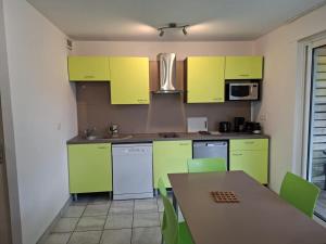 eine Küche mit gelben Schränken und einem Tisch mit grünen Stühlen in der Unterkunft Cottage Le Vau 2, draps fournis, piscine in Chaveignes + 9 Fotos