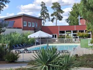 ein Pool mit Sonnenschirm und Stühlen sowie ein Gebäude in der Unterkunft Cottage Le Vau 2, draps fournis, piscine in Chaveignes