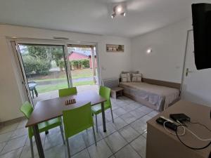 ein Wohnzimmer mit einem Tisch und grünen Stühlen in der Unterkunft Cottage Le Vau 2, draps fournis, piscine in Chaveignes