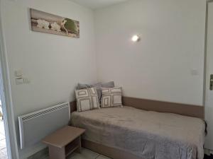 ein kleines Schlafzimmer mit einem Bett und einem Tisch in der Unterkunft Cottage Le Vau 2, draps fournis, piscine in Chaveignes