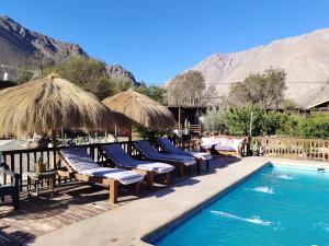 a resort with a pool and chairs and a mountain at Casa Puente en Rivadavia in Vicuña