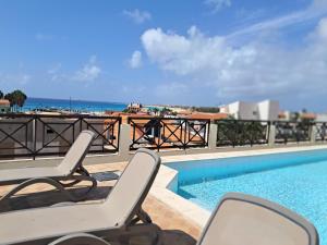 a view of a swimming pool with two chairs and the ocean at Patio Antigo 218 in Santa Maria